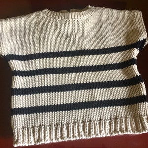 May include: A beige and black striped knitted sweater with short sleeves.