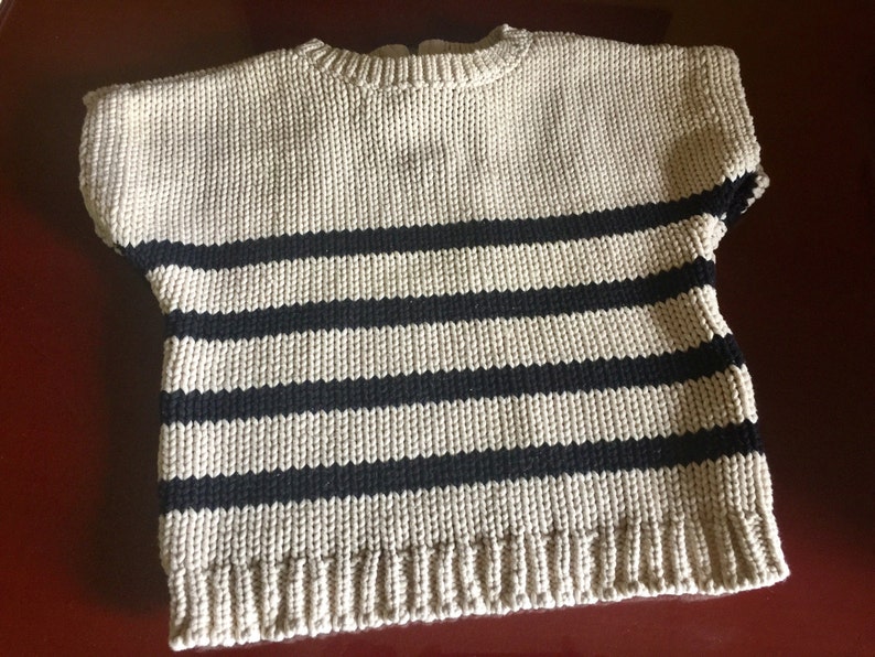 May include: A beige and black striped knitted sweater with short sleeves.