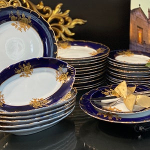 May include: A set of blue and gold porcelain dinnerware with a floral design. The set includes plates, bowls, and a serving platter.