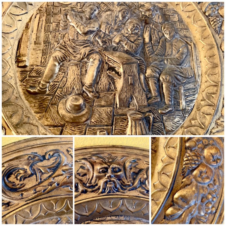 K&ouml;nnte beinhalten: Eine runde Wandplatte aus Messing mit einem erhabenen, gepr&auml;gten Design. Die Mitte zeigt eine Szene von Menschen, die um einen Tisch versammelt sind, w&auml;hrend der &auml;u&szlig;ere Rand einen dekorativen Rand aus Bl&auml;ttern und Ranken hat.