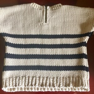 May include: A beige and black striped knitted sweater with short sleeves and a zipper at the back of the neck.
