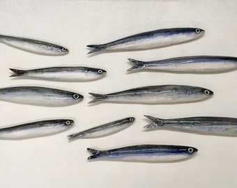 50 ceramic anchovies of various sizes, handmade. To be applied to the wall using the small holes on the back. Decorative wall fish.