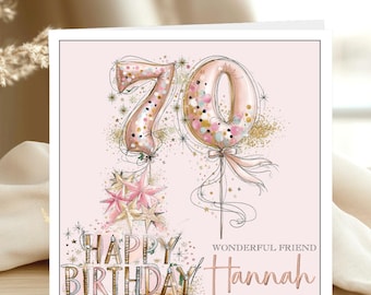 May include: A square birthday greeting card with a pale pink background featuring the number 70 in large, rose gold balloon-style lettering filled with confetti. Below are pink and gold stars, the text HAPPY BIRTHDAY, and WONDERFUL FRIEND Hannah.