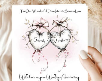 May include: A wedding anniversary card with a watercolor design. The card features two heart-shaped balloons with the names "Sarah" and "Matthew" on them, tied with pink ribbons. The text reads "To Our Wonderful Daughter & Son-in-Law" and "With love on your Wedding Anniversary."