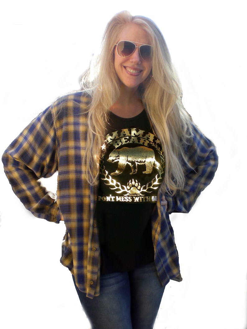 Puede incluir: Una camiseta negra con un dise&ntilde;o en l&aacute;mina dorada que dice "Mama Bear" con una silueta de oso y las palabras "Don't Mess With" debajo.
