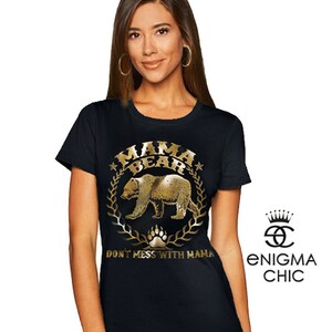 Puede incluir: Camiseta negra con un gr&aacute;fico dorado de un oso y el texto "Mama Bear" y "Don't Mess With Mama".