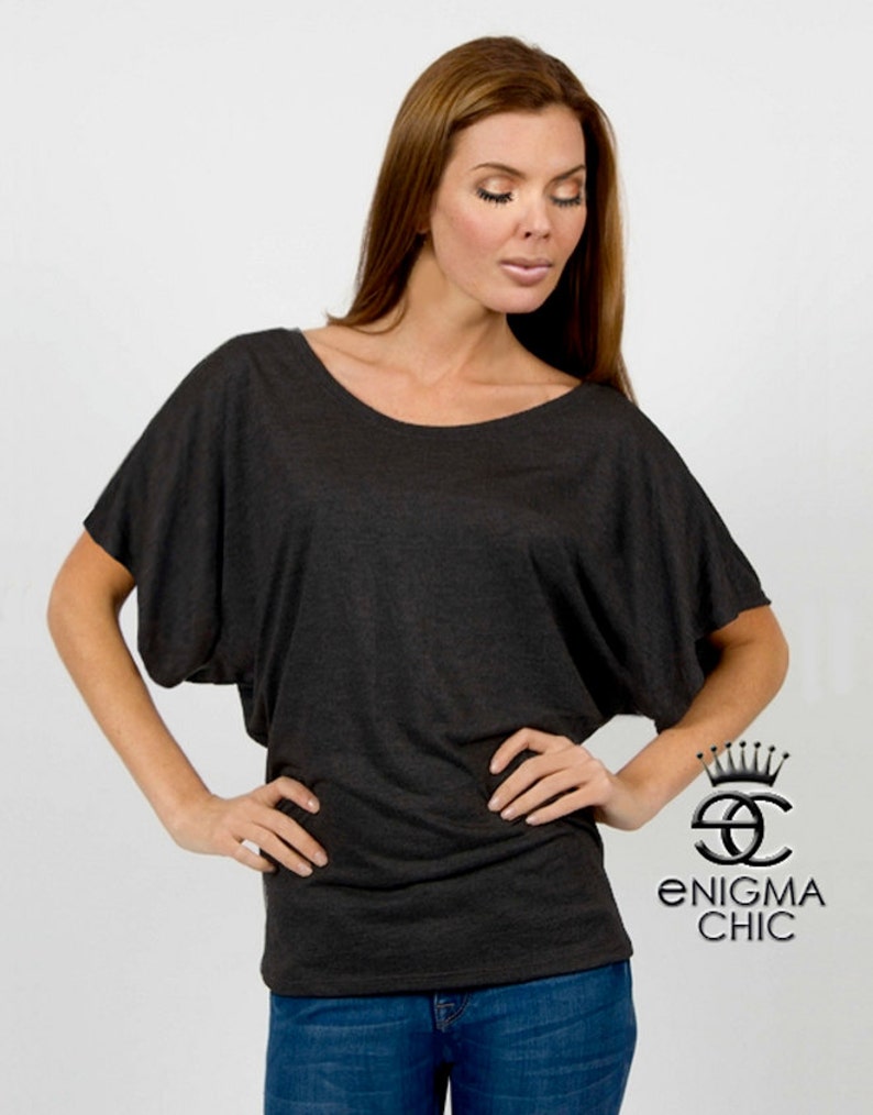 Pu&ograve; includere: Una maglietta grigia scura, larga, a maniche corte e scollo rotondo. La maglietta &egrave; realizzata in un tessuto morbido e confortevole e ha una vestibilit&agrave; rilassata. La modella indossa la maglietta con jeans blu.