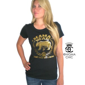 Puede incluir: Una camiseta negra con un gr&aacute;fico dorado de un oso y el texto "Mama Bear Don't Mess With Mama".