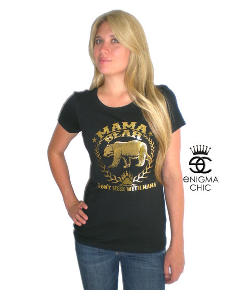Puede incluir: Una camiseta negra con un gr&aacute;fico dorado de un oso y el texto "Mama Bear Don't Mess With Mama".