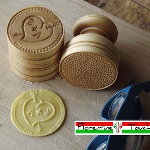 May include: A set of wooden cookie cutters featuring a heart design and the initials A & S. The cutters are on a wooden surface with a yellow cookie that has been pressed with the cutter.