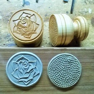 May include: Two sets of wooden cookie cutters, one with a rose design and the other with a textured pattern. The cutters are on a wooden surface.