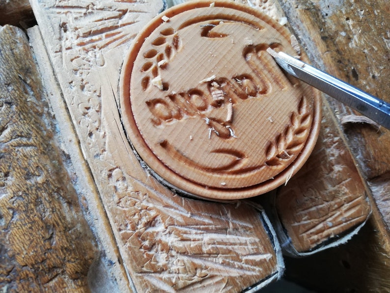 May include: A close-up of a wooden stamp with the word "Duomo" carved into it. The stamp is being carved with a small knife.