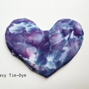 Puede incluir: Una almohada para los ojos con forma de coraz&oacute;n, te&ntilde;ida en azul marino, morado y blanco. La almohada est&aacute; hecha de tela suave y es perfecta para relajarse.