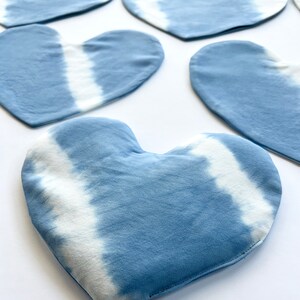 Pode incluir: Cinco pe&ccedil;as de tecido em forma de cora&ccedil;&atilde;o azul e branco tie-dye. O tecido tem um fundo azul claro com padr&otilde;es tie-dye brancos.
