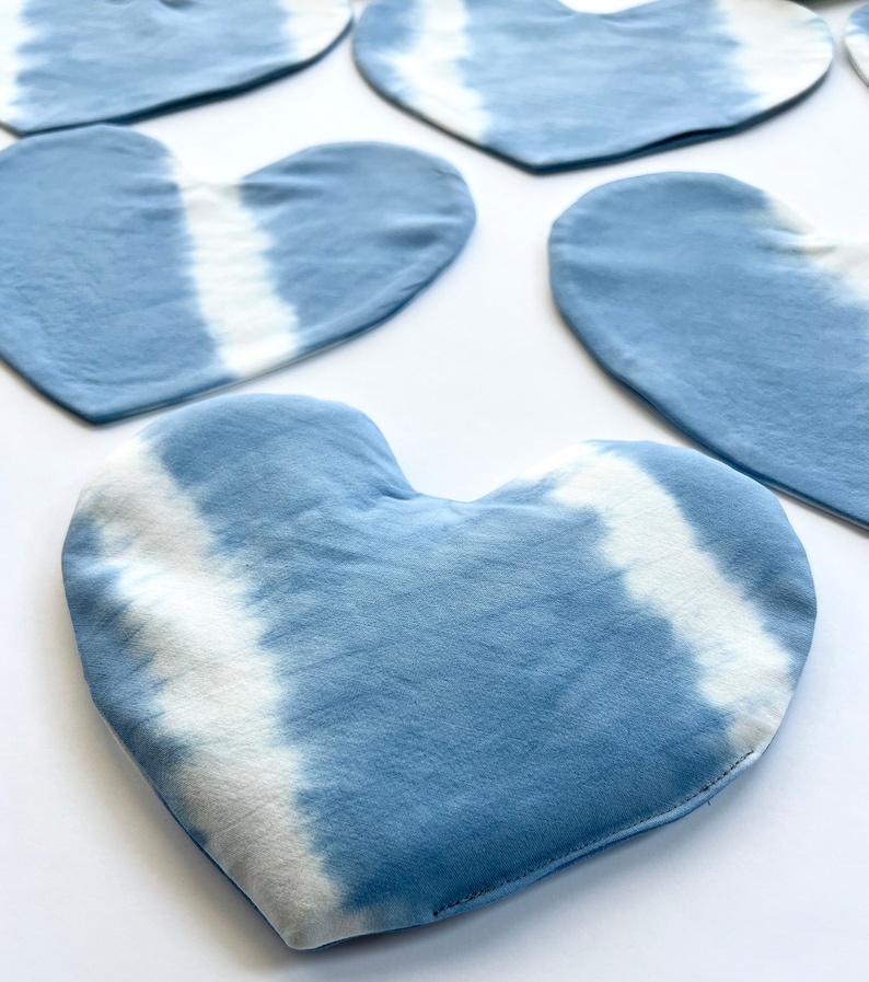 Pode incluir: Cinco pe&ccedil;as de tecido em forma de cora&ccedil;&atilde;o azul e branco tie-dye. O tecido tem um fundo azul claro com padr&otilde;es tie-dye brancos.