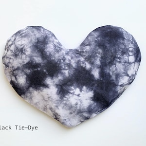 Puede incluir: Una almohada para los ojos en forma de coraz&oacute;n, con estampado tie-dye en blanco y negro.