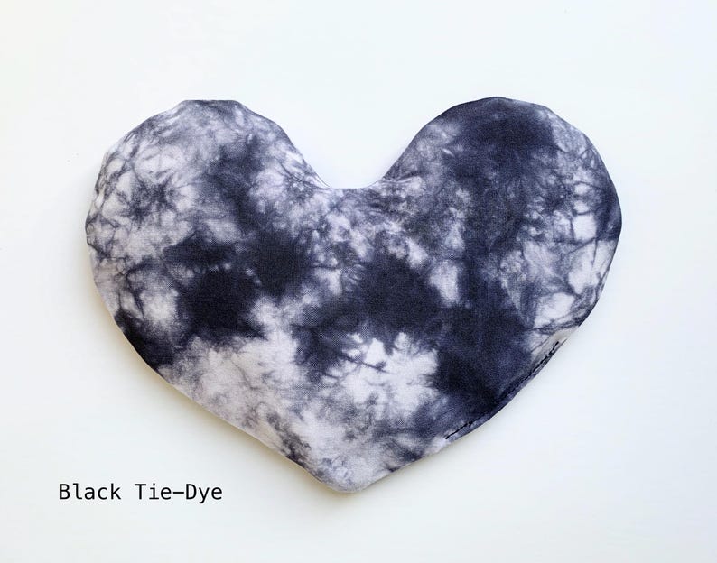Puede incluir: Una almohada para los ojos en forma de coraz&oacute;n, con estampado tie-dye en blanco y negro.