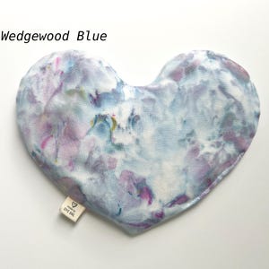 Puede incluir: Una m&aacute;scara para los ojos de tela azul y p&uacute;rpura te&ntilde;ida anudada en forma de coraz&oacute;n con el texto "Made by EYE GIRL" en una etiqueta blanca.