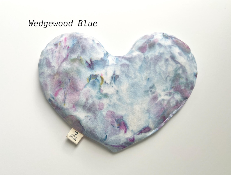 Puede incluir: Una m&aacute;scara para los ojos de tela azul y p&uacute;rpura te&ntilde;ida anudada en forma de coraz&oacute;n con el texto "Made by EYE GIRL" en una etiqueta blanca.