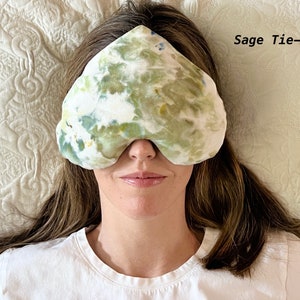 Puede incluir: Una persona lleva una m&aacute;scara para dormir de color verde salvia con estampado tie-dye. La m&aacute;scara est&aacute; hecha de tela suave y tiene un estampado tie-dye.