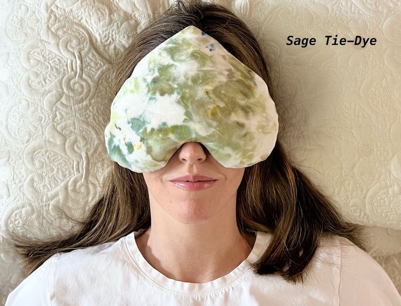 Puede incluir: Una persona lleva una m&aacute;scara para dormir de color verde salvia con estampado tie-dye. La m&aacute;scara est&aacute; hecha de tela suave y tiene un estampado tie-dye.