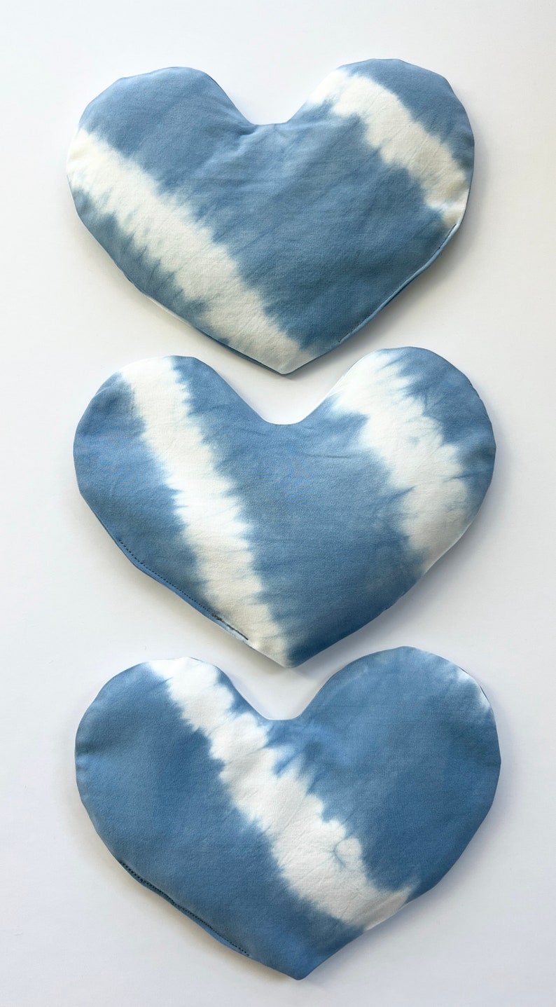 Pode incluir: Tr&ecirc;s almofadas em forma de cora&ccedil;&atilde;o azul e branco com tie-dye. As almofadas s&atilde;o feitas de um tecido de algod&atilde;o macio e t&ecirc;m um visual sutil e desbotado.