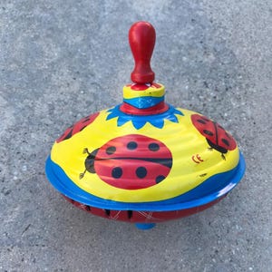 Toupie vintage LBZ en métal, décorée d'une coccinelle et d'un bouton en bois rouge, fabriquée en Allemagne de l'Ouest.
