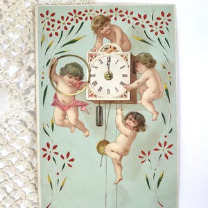May include: Vintage postcard with cherubs and a clock. The clock shows midnight, with cherubs around it. The background is a light blue with red and green floral accents. The postcard is rectangular.