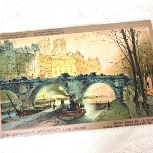 May include: A vintage postcard titled CARTE TRANSPARENTE featuring an illustration of the Seine river in Paris with a stone bridge, a small boat, and buildings in the background. The text reads PETIT BRAS DE LA SEINE, PONT-NEUF, NOTRE-DAME DE PARIS.