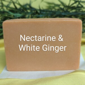May include: A rectangular bar of soap with a light orange color. The soap has the text "Nectarine & White Ginger" printed on it.