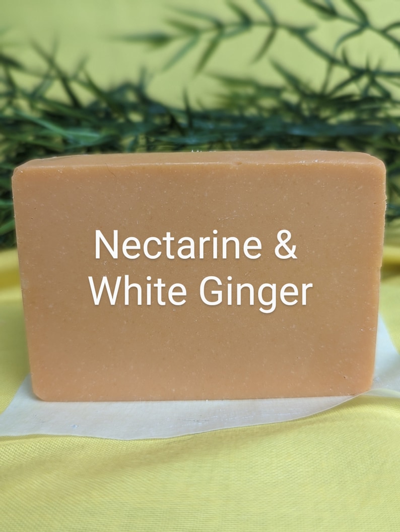 May include: A rectangular bar of soap with a light orange color. The soap has the text "Nectarine & White Ginger" printed on it.