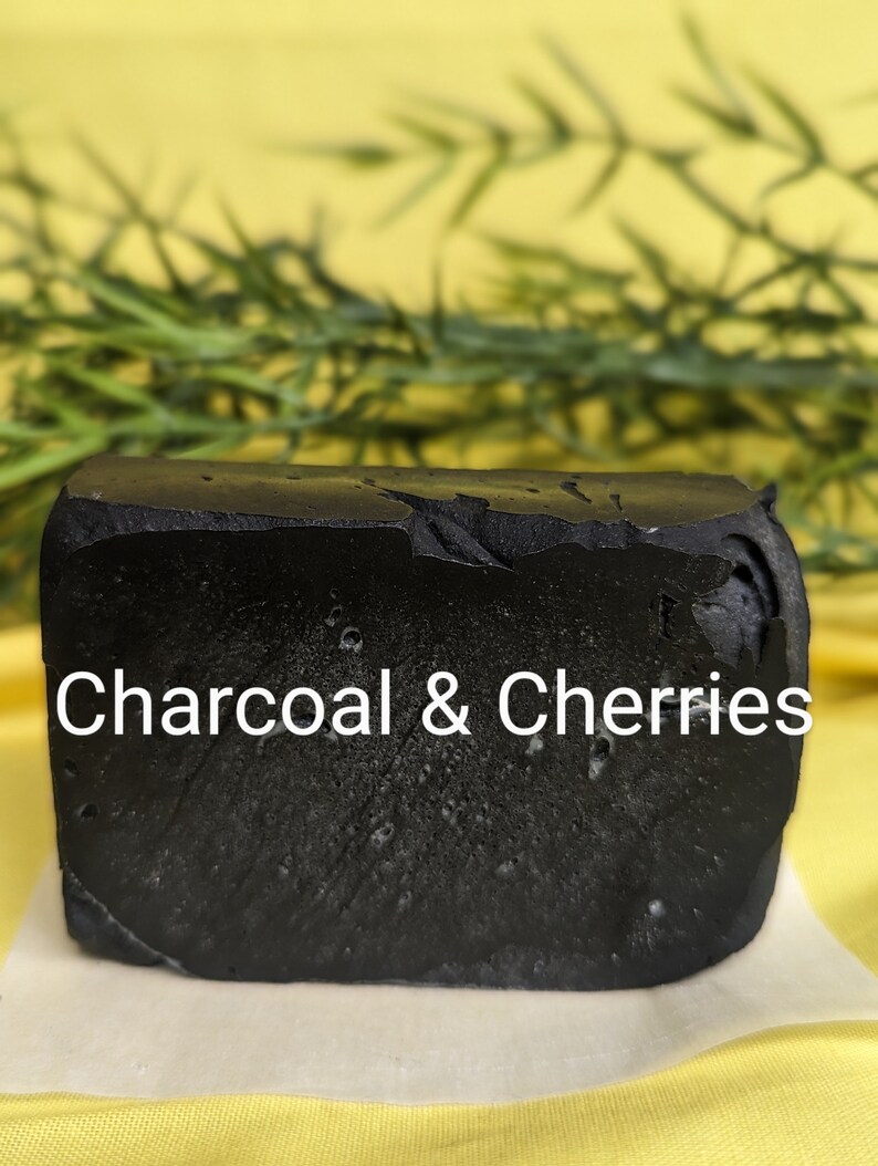 May include: A black bar of soap with the text "Charcoal & Cherries" printed on it. The soap is sitting on a white surface.