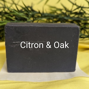 May include: A dark gray bar of soap with the text "Citron & Oak" printed on the front.