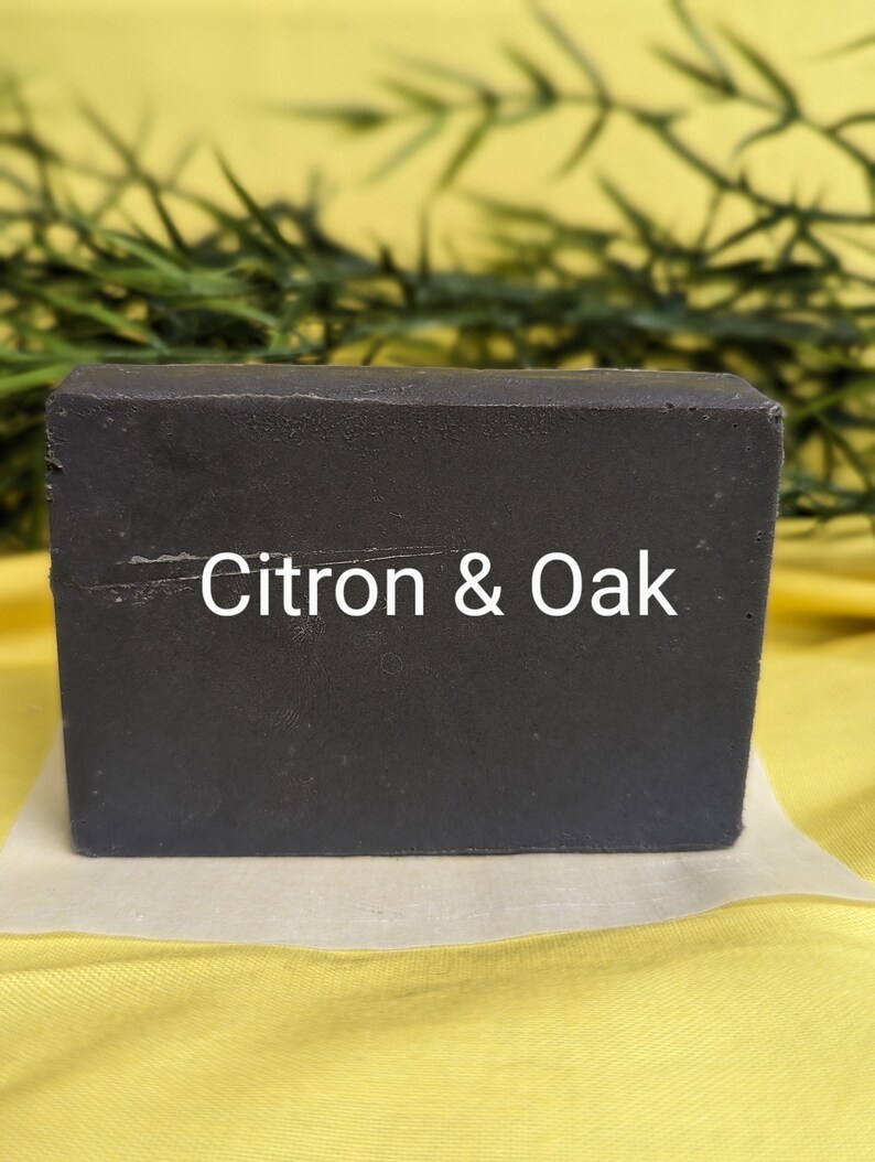 May include: A dark gray bar of soap with the text "Citron & Oak" printed on the front.