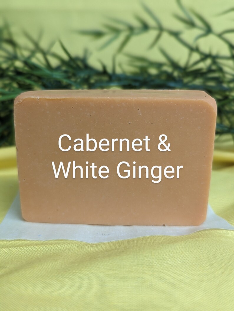 May include: A rectangular bar of soap with a light brown color. The soap has the text "Cabernet & White Ginger" printed on the front.