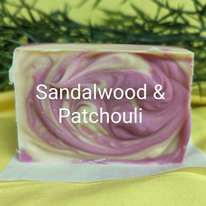 May include: A bar of handmade soap with a swirl design in shades of pink and white. The soap is labeled "Sandalwood & Patchouli".
