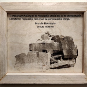 May include: A framed black and white image of a bulldozer with a quote by Marvin Heemeyer, "I was always willing to be reasonable until I had to be unreasonable. Sometimes reasonable men must do unreasonable things." The quote is dated 10/28/51-06/04/2004.