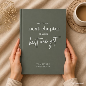 May include: A dark olive green hardcover book featuring the white printed text "MAY YOUR next chapter BE YOUR best one yet" followed by "TOM HARDY CHAPTER 50" centered on the front cover. The book has a smooth, matte finish and a clean, minimalist design.
