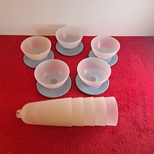 May include: Five white frosted glass bowls with blue saucers, and a stack of four white frosted glass bowls.