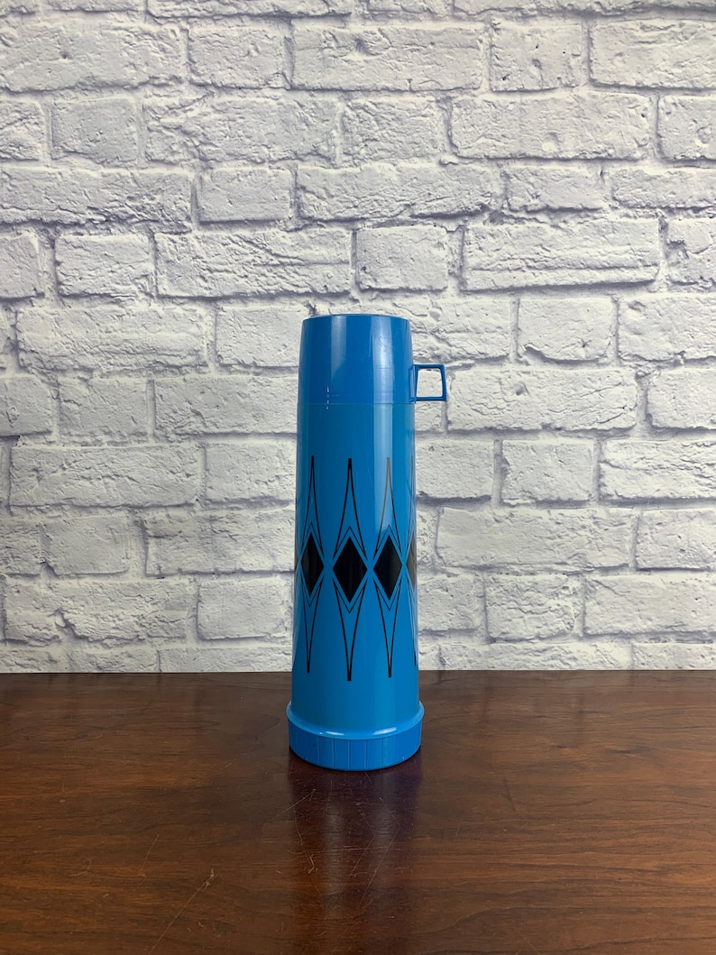May include: A blue and black thermos with a geometric design. The thermos has a black handle and a blue lid.