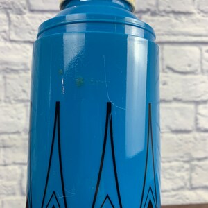 May include: A blue and black patterned thermos with a white lid. The thermos has a geometric design with black triangles on a blue background.