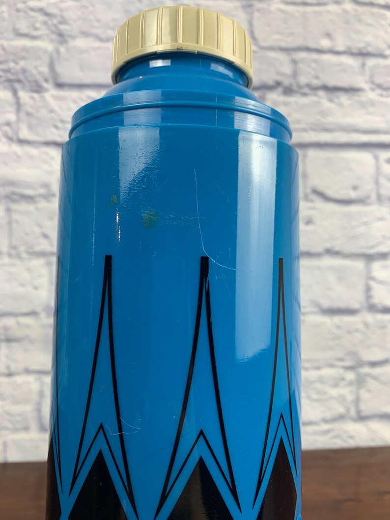 May include: A blue and black patterned thermos with a white lid. The thermos has a geometric design with black triangles on a blue background.