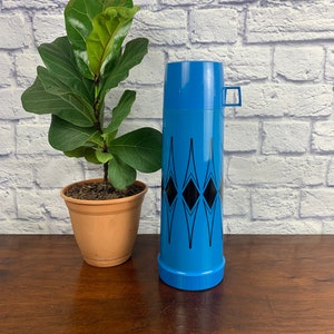 May include: A blue and black thermos with a geometric pattern. The thermos has a lid and a handle.