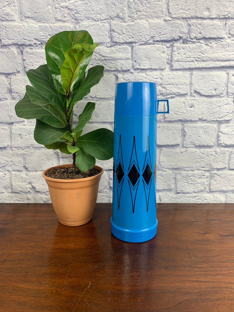 May include: A blue and black thermos with a geometric pattern. The thermos has a lid and a handle.