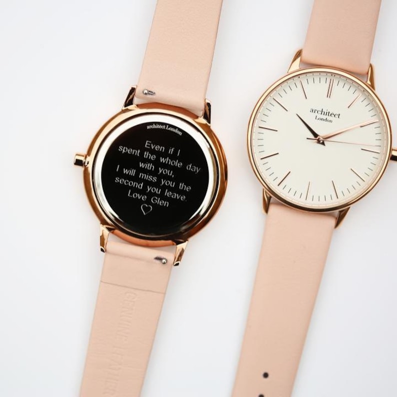 May include: Two rose gold watches with pink leather bands. The watch on the left has an engraved message on the back that reads "Even if I spent the whole day with you, I will miss you the second you leave. Love Glen". The watch on the right has a white face with black markings and the words "architect London" printed on it.