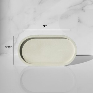 Peut inclure: Un plateau ovale en b&eacute;ton de couleur gris clair avec un bord sur&eacute;lev&eacute;. Le plateau mesure 17,78 cm de long et 9,53 cm de large.