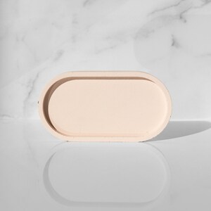 Peut inclure: Un plateau ovale de couleur beige clair avec un bord sur&eacute;lev&eacute;. Le plateau est fait d'un mat&eacute;riau textur&eacute; et a une finition lisse et mate.