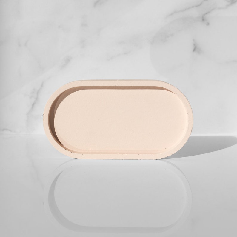 Peut inclure: Un plateau ovale de couleur beige clair avec un bord sur&eacute;lev&eacute;. Le plateau est fait d'un mat&eacute;riau textur&eacute; et a une finition lisse et mate.