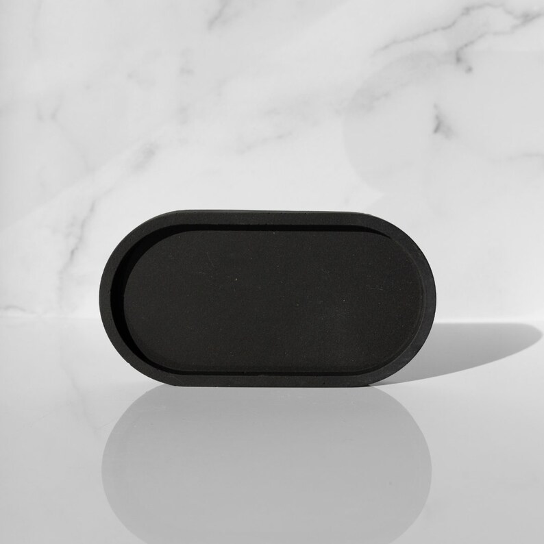 Peut inclure: Un plateau ovale noir avec un bord sur&eacute;lev&eacute;. Le plateau est fait d'un mat&eacute;riau lisse et mat et est parfait pour contenir de petits objets.