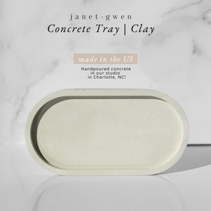 Peut inclure: Un plateau ovale en b&eacute;ton gris clair avec un bord sur&eacute;lev&eacute;. Le plateau est fabriqu&eacute; aux &Eacute;tats-Unis et coul&eacute; &agrave; la main dans un atelier &agrave; Charlotte, Caroline du Nord. Le texte "janet.gwen Concrete Tray | Clay made in the US Handpoured concrete in our studio in Charlotte, NC!" est visible sur l'image.